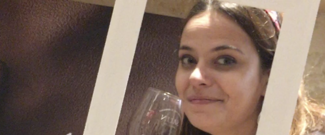 Charlotte souriante avec un verre de vin rouge à la main, moment simple et joyeux autour du vin, sans cérémonie, dans une ambiance conviviale.