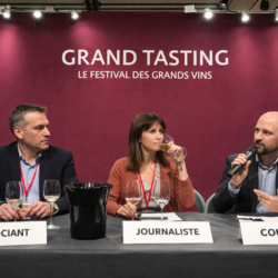 Panel de dégustation de vins lors des Primeurs de Bordeaux, trois professionnels (négociant, journaliste, courtier) assis derrière une table avec verres de dégustation et crachoir