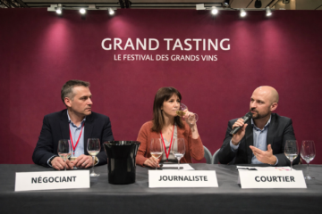 Panel de dégustation de vins lors des Primeurs de Bordeaux, trois professionnels (négociant, journaliste, courtier) assis derrière une table avec verres de dégustation et crachoir