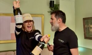 Charlotte souriante levant deux bouteilles de La Bringuette lors du lancement au Georges au Bouscat, aux côtés de Fabien le winemaker, dans une ambiance festive et conviviale.