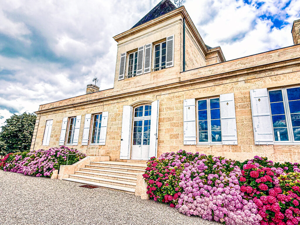 Façade de la demeure du Château Brane-Cantenac à Margaux entourée d'hortensias en fleurs lors du centenaire de la propriété familiale.