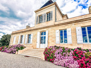 Façade de la demeure du Château Brane-Cantenac à Margaux entourée d'hortensias en fleurs lors du centenaire de la propriété familiale.