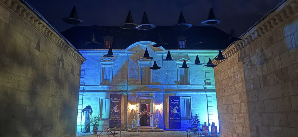 Château Siaurac illuminé de bleu pour le Château Magique de Bordeaux, avec des chapeaux de sorciers suspendus dans la cour pendant Halloween 2026.