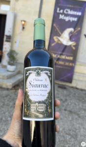 Bouteille de Château Siaurac en appellation Lalande-de-Pomerol, avec son étiquette spéciale Le Château Magique, photographiée devant l'Académie de Magie.